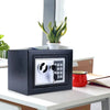 A black digital lock safe box sits on a white desk next to a potted plant.