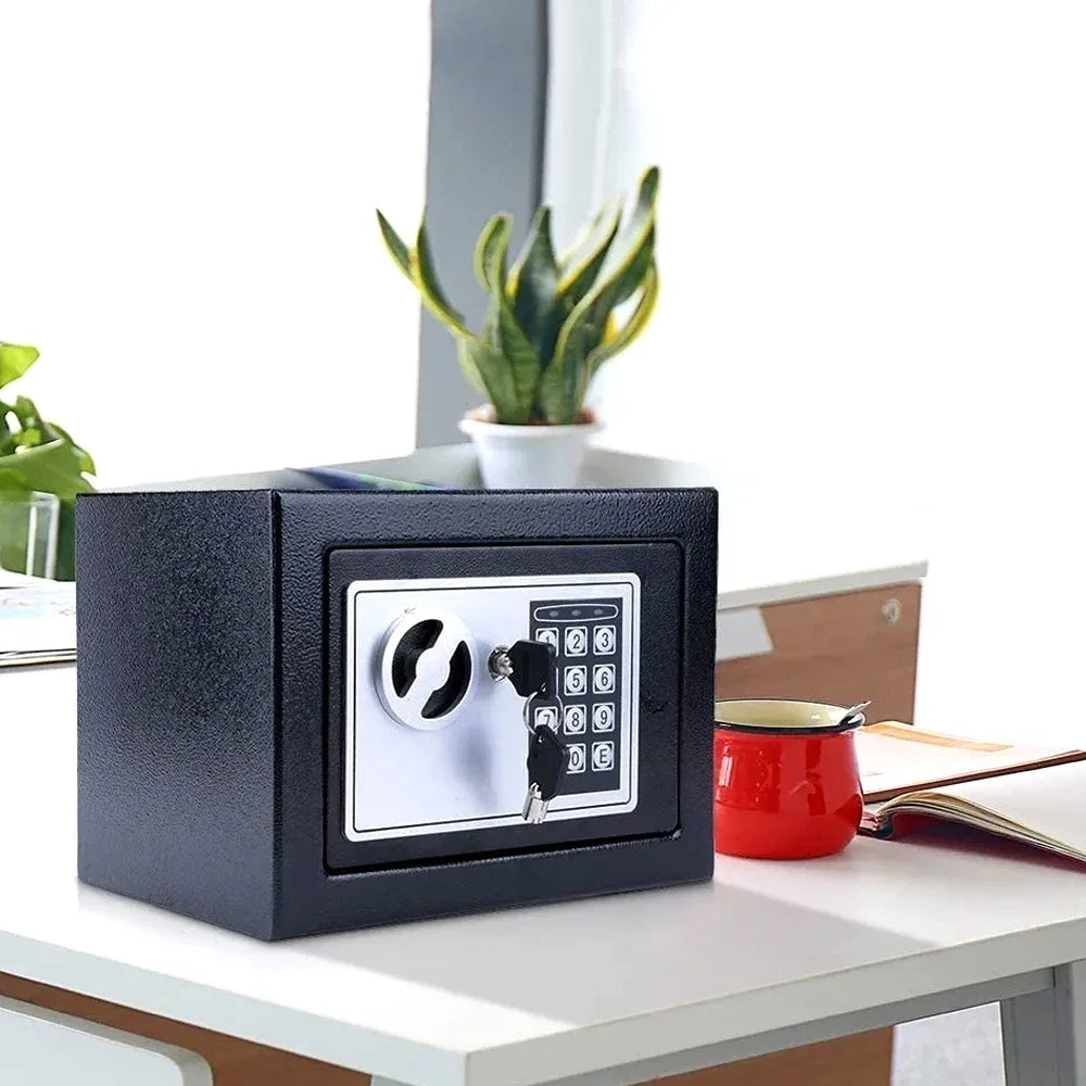 A black digital lock safe box sits on a white desk next to a potted plant.