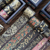 A set of metallic gold washi tape rolls in various colors and patterns displayed on a wooden surface.