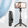 A black Bluetooth selfie stick with an LED fill light is mounted on a tripod stand, showing a woman's portrait.