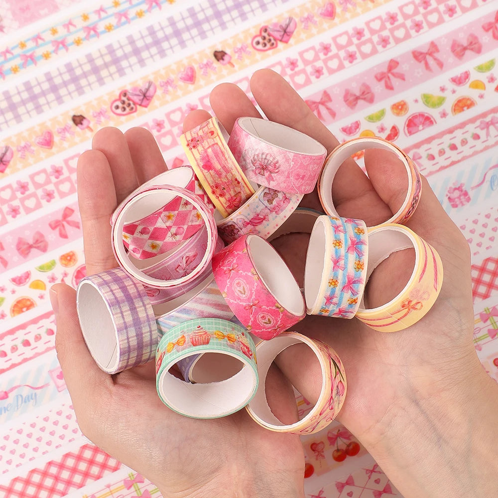A hand holds a set of pink and floral patterned washi tape rolls on a pink and white patterned cloth.