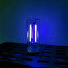A clear glass bulb with a bright white filament is illuminated against a deep blue background.
