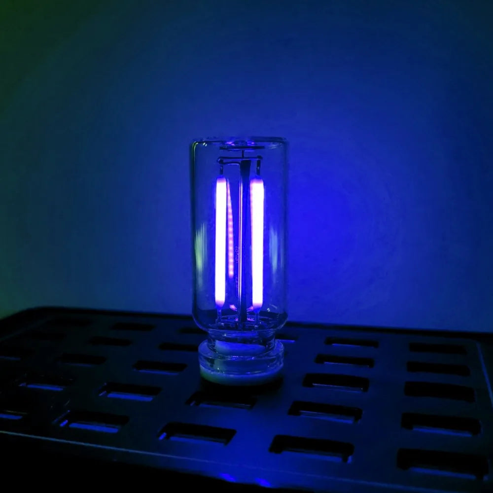 A clear glass bulb with a bright white filament is illuminated against a deep blue background.