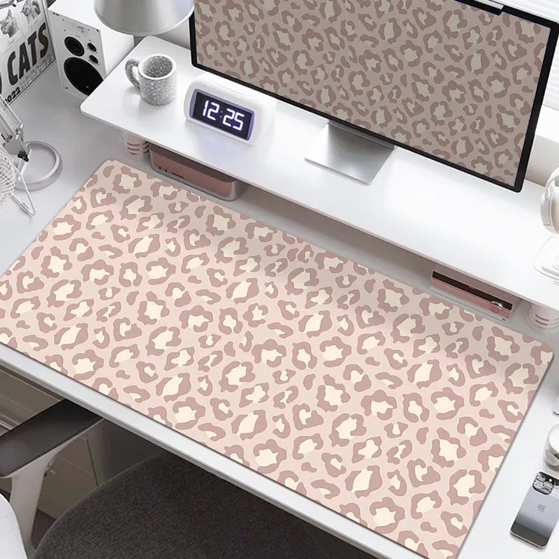 A large leopard print desk pad is displayed on a white desk next to a digital clock and a computer monitor.