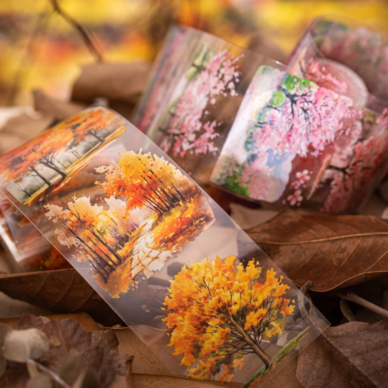 A collection of colorful forest botanical PET tape samples in various shades of pink, orange, and yellow resting on brown lea