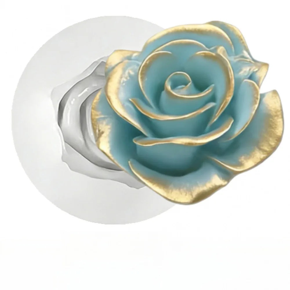 A close-up of a floral design featuring a blue-green rose with gold accents on a white background.