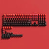 A close-up view of a red PBT keycap set for mechanical keyboards arranged on a solid red background.