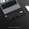 A close-up view of a black mechanical keyboard and laptop with a white mouse on a dark surface.
