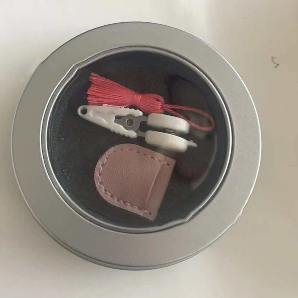 مقص خياطة صغير ذو طرف مستقيم، بمقبض أبيض وسلك أحمر، داخل وعاء فضي.