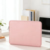 A pink waterproof PU leather laptop sleeve resting on a white desk next to a laptop and some books.