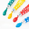 A set of six tubes of vibrant gouache paint in various colors including green, yellow, red, and blue.