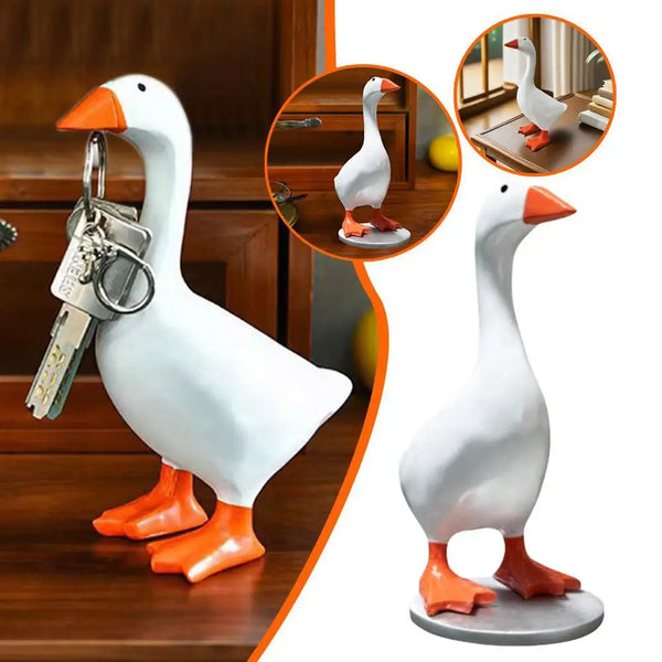 A white ceramic duck figurine with orange feet and a magnetic key holder attached, displayed on a wooden surface.