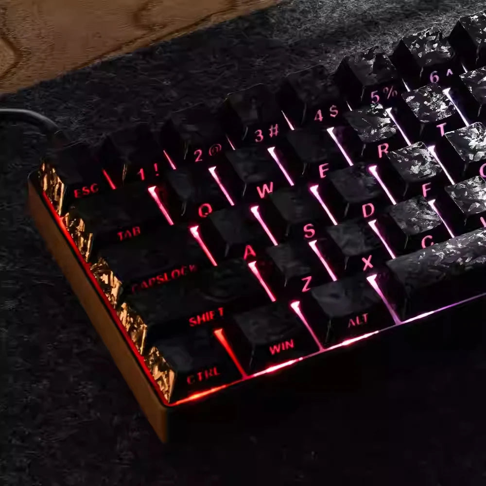 Close-up of a black mechanical keyboard with pink and purple backlit keycaps resting on a dark surface.