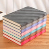 A stack of colorful, ultra thick universal A5/A4 notebooks for school and work on a wooden surface.