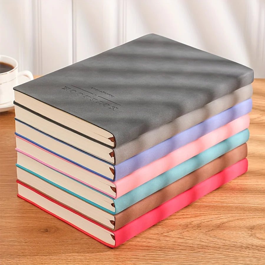 A stack of colorful, ultra thick universal A5/A4 notebooks for school and work on a wooden surface.
