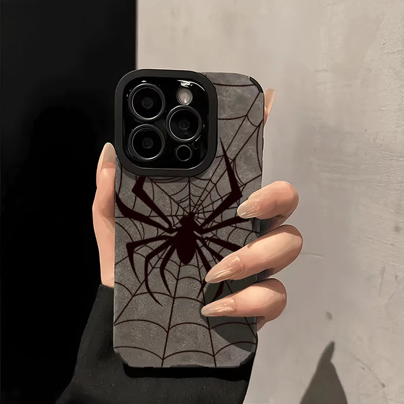 A hand holds a phone case featuring a black spider web design on a gray background.