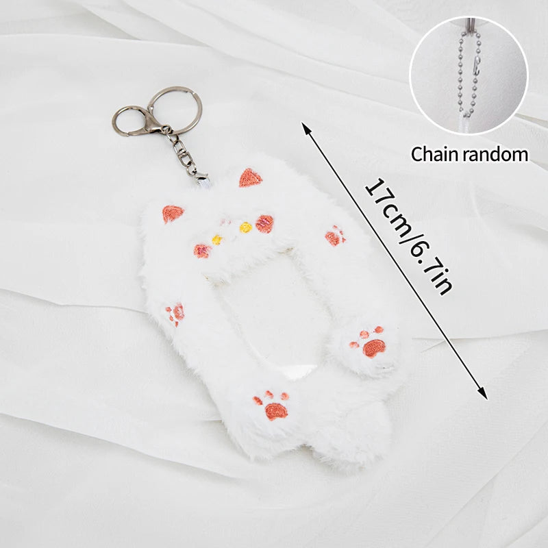 White plush photocard holder with paw prints and a chain, shown against a white fabric background.