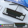 Un clavier mécanique noir et gris 61 touches sur un bureau à côté d'un moniteur d'ordinateur.
