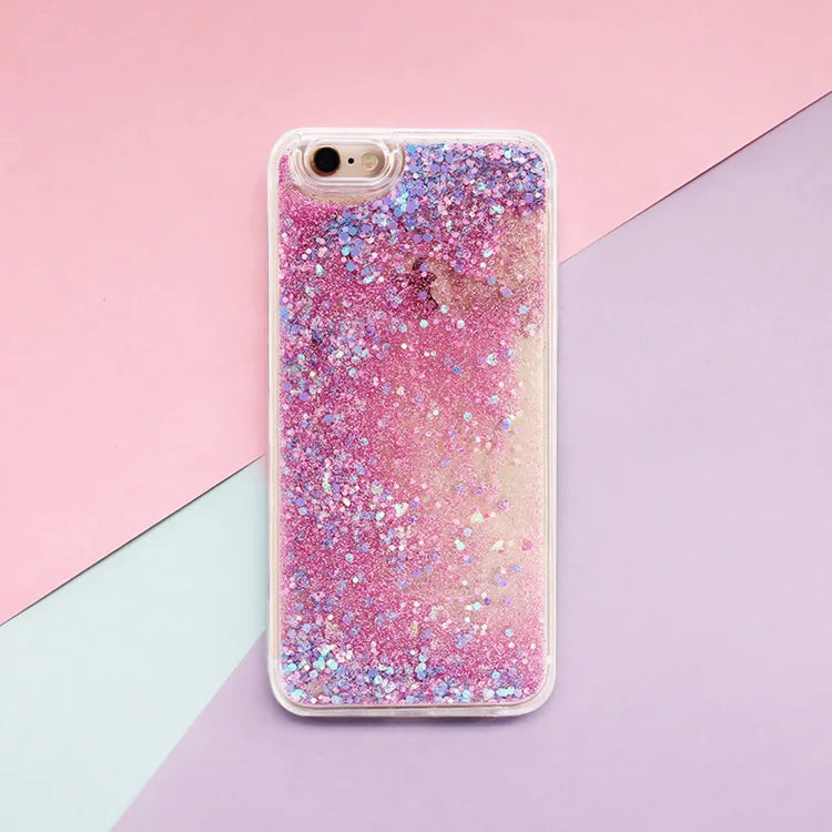 A clear phone case filled with pink and blue glitter and iridescent particles set against a pastel background.