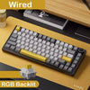 Schwarze mechanische Tastatur mit gelben Akzenten und RGB-Beleuchtung auf einem Holzschreibtisch.
