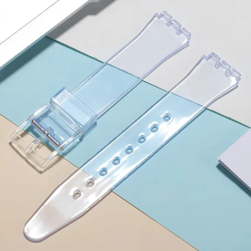 Clear silicone watch strap with replacement tools shown on a light blue background.