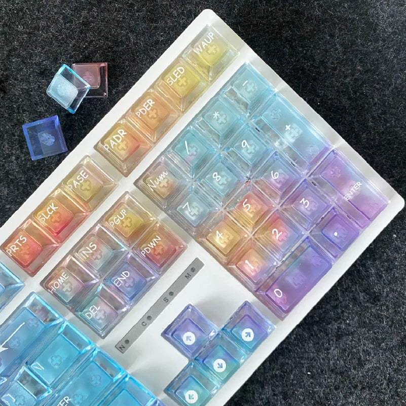 A white plastic tray holds a set of colorful rainbow shine PC keycaps for a mechanical keyboard.