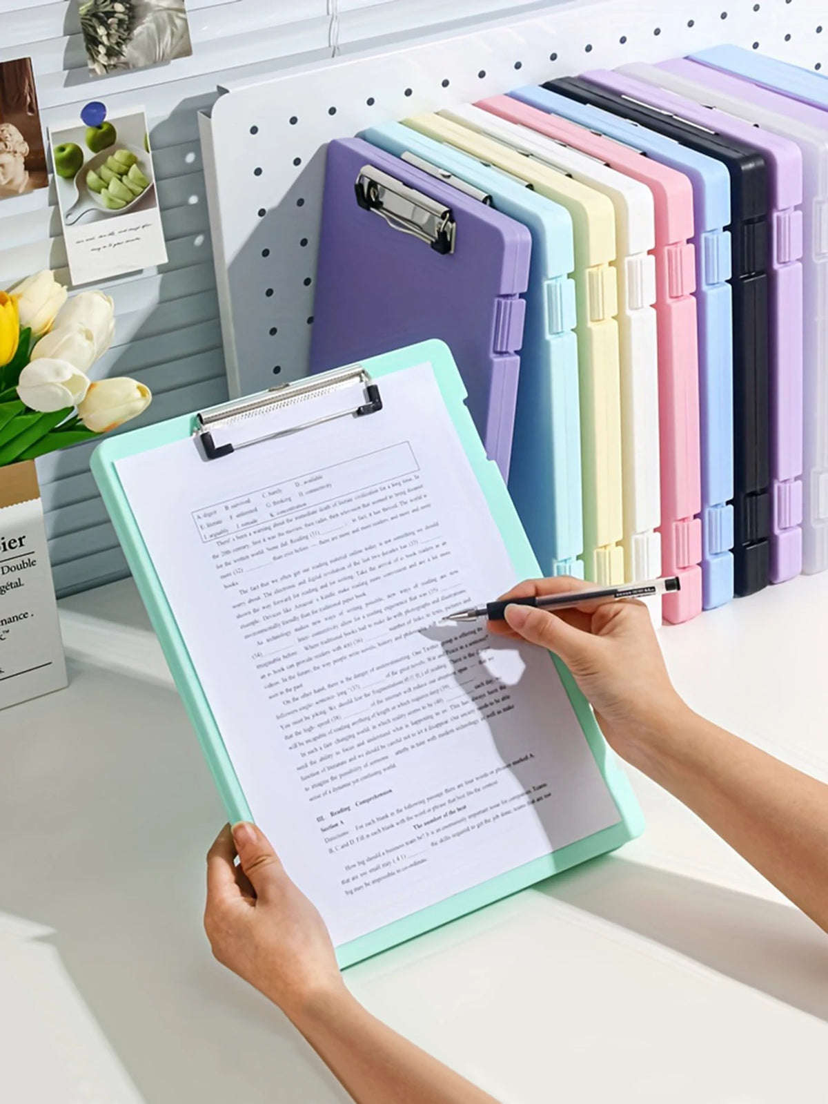 A hand holds an open A4 document and photo storage file box next to a row of colorful file boxes.