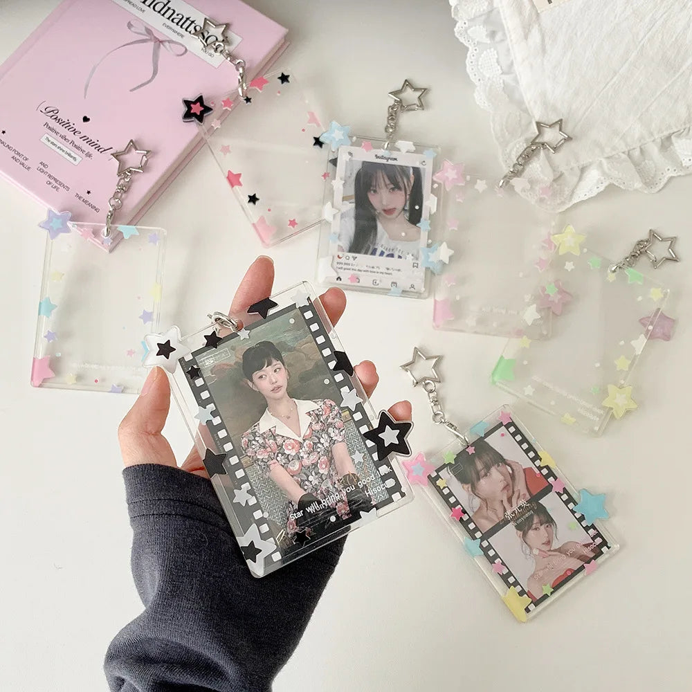 Une main tient un pendentif porte-photocard en acrylique avec une photo de personne, entouré de petits charms en forme d'étoi