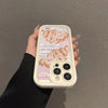 A beige phone case with a croissant newspaper pattern is held in a hand against a gray wall.
