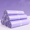 A stack of purple waterproof self-adhesive courier mailer bags rolled up on a white surface.