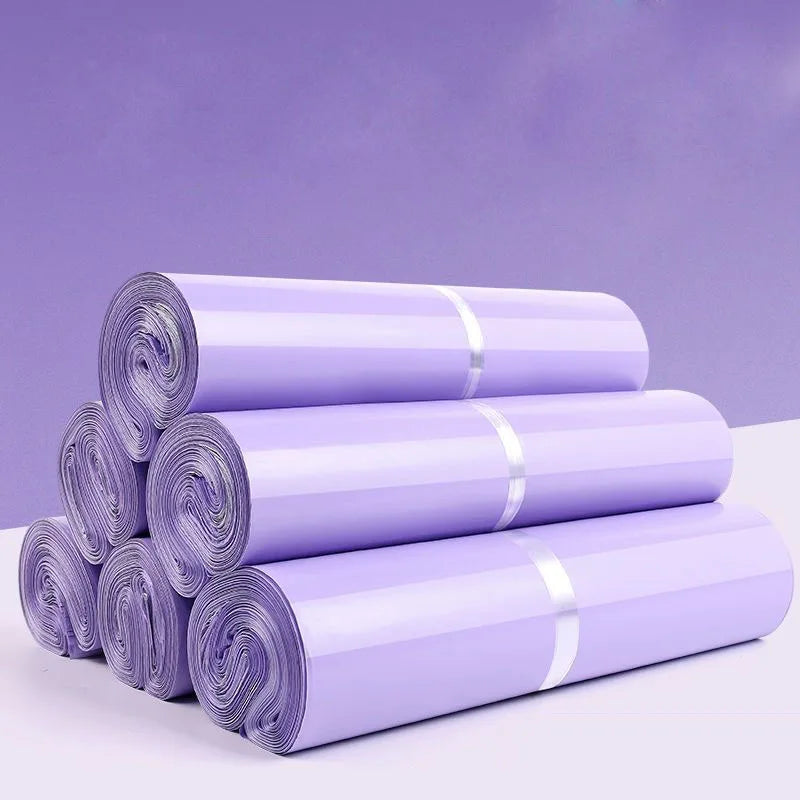A stack of purple waterproof self-adhesive courier mailer bags rolled up on a white surface.