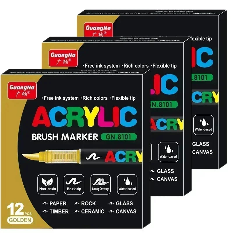 A set of twelve gold acrylic brush markers with various tips and colors packaged in black boxes.