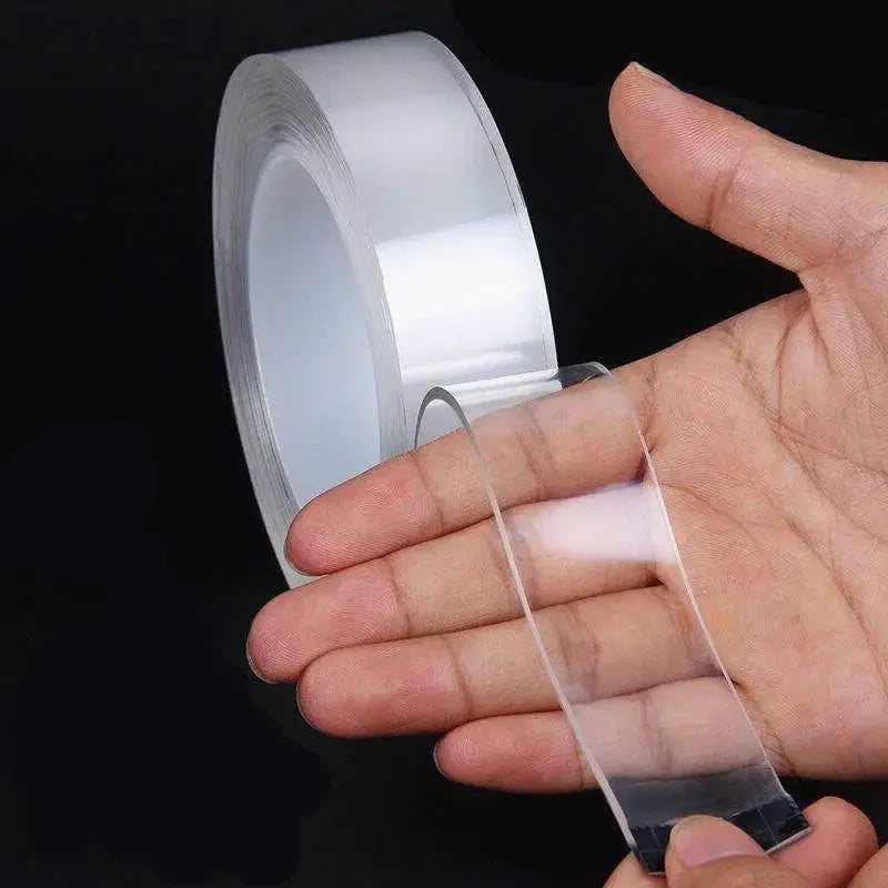 A hand holds a roll of heavy duty clear double-sided gap tape and a piece of the tape.
