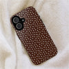 A brown phone case with white polka dots resting on a fluffy beige fabric.