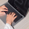 Hände tippen auf einem Laptop mit einer ultraflachen Silikon-Tastaturabdeckung.