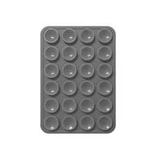 A gray reusable silicone suction phone mount with multiple circular holes for mounting.