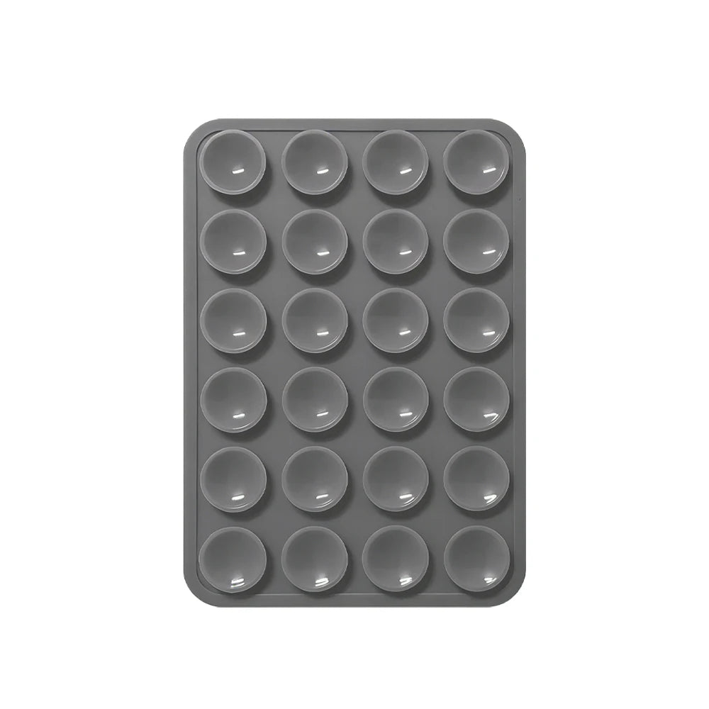 A gray reusable silicone suction phone mount with multiple circular holes for mounting.
