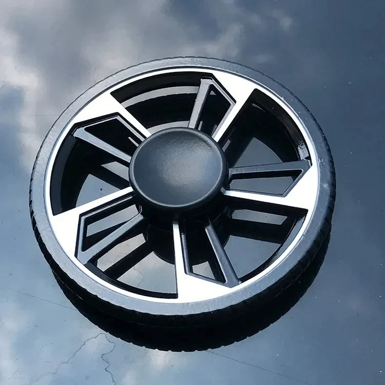 A close-up view of a black and silver metal fidget spinner against a cloudy blue sky.