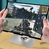 A hand holds a foldable tablet displaying a first-person shooter game, resting on a silver stand.
