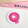 A pink magnetic phone grip and stand with a foldable ring is shown on a white surface.