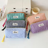 A collection of colorful zippered pencil cases in various patterns and colors, resting on a white surface.