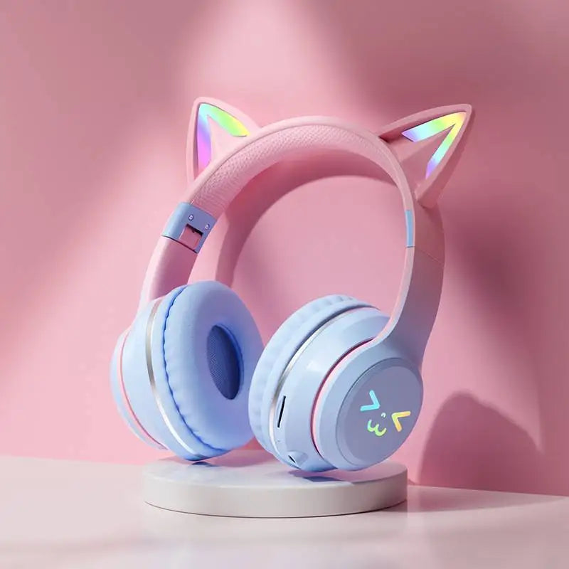 Pink gradient RGB cat ear Bluetooth headphones resting on a white stand.