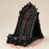 A black gothic skull phone stand with intricate detailing shown from the side.