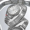 A close-up view of a polished stainless steel watch with a silver dial and bracelet on a reflective surface.