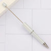 A silver and white DIY beadable pen set with a black ink tip resting on a white tiled surface.