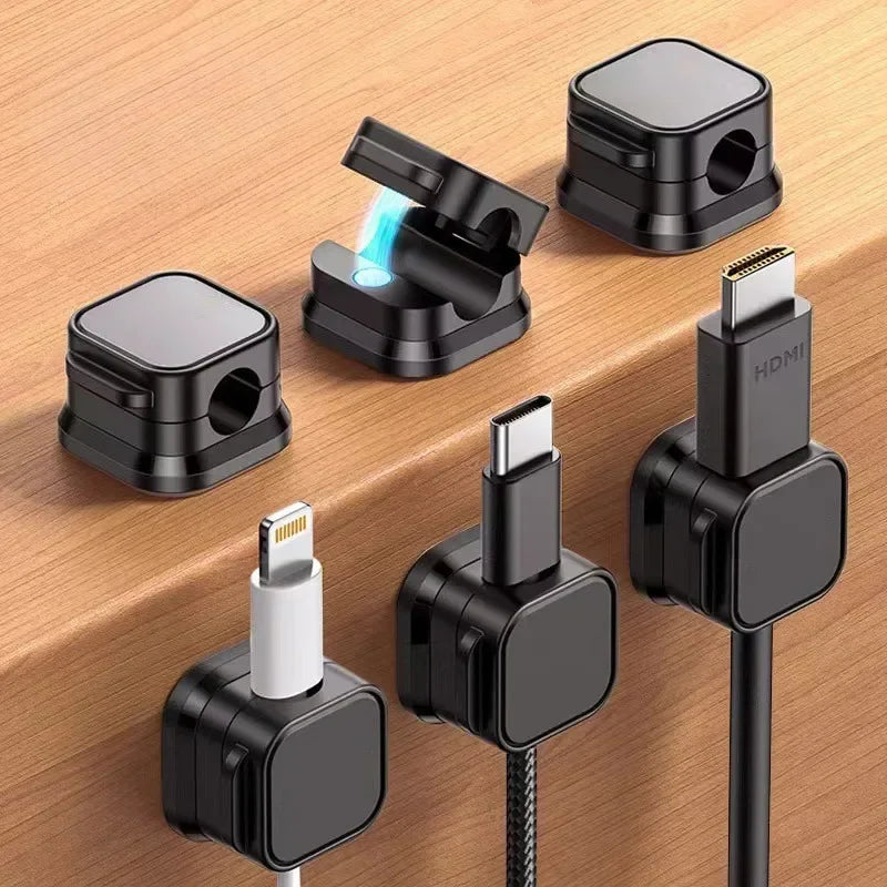 Six magnetic cable organizer clips in black and white are shown on a wooden surface.