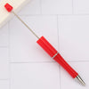 A red DIY beadable pen with a silver tip and a red cap resting on a white surface.