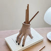 A hand-shaped decoration made of spooky resin palm leaves with wooden sticks, resting on a white book.