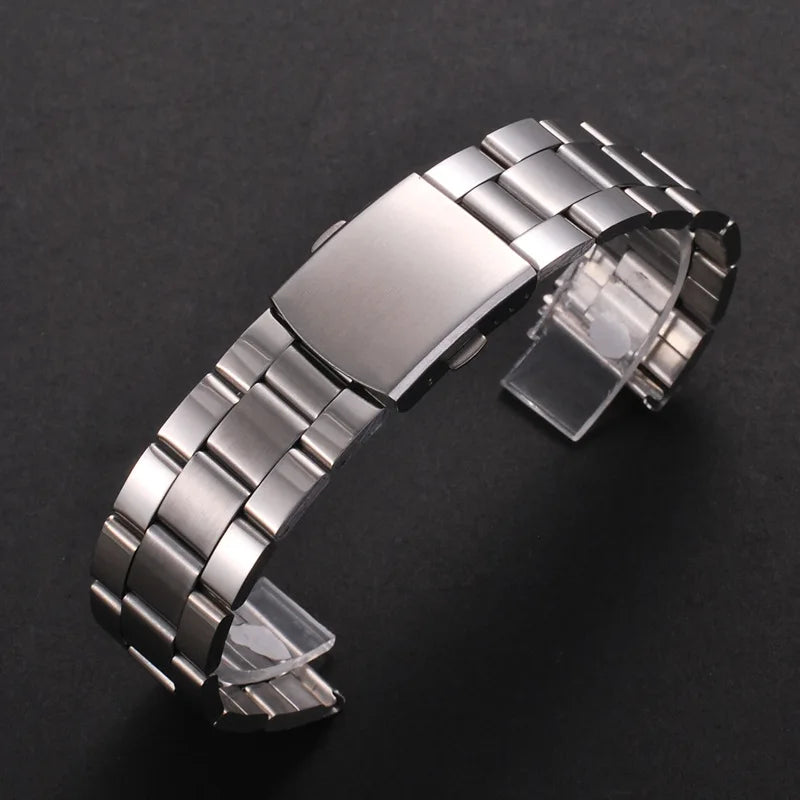 A stainless steel watch band with a folding safety clasp is shown on a dark background.