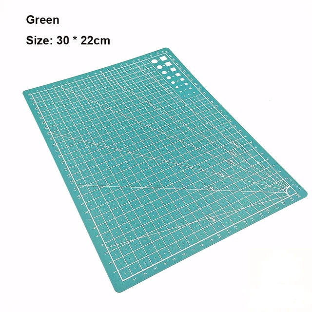 A green art cutting tool with a grid pattern and a circular hole for rotating.